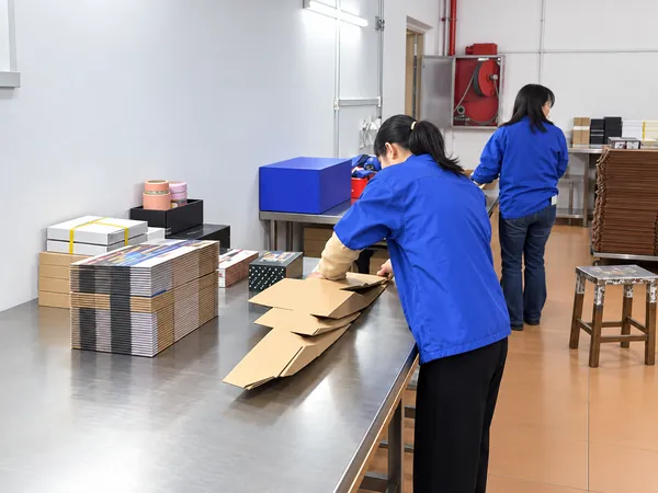 Staff in blue work uniforms checking and packing finished boxes